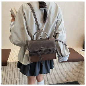 Detailed close-up of retro brown leather handbag with contrast stitching and gold logo