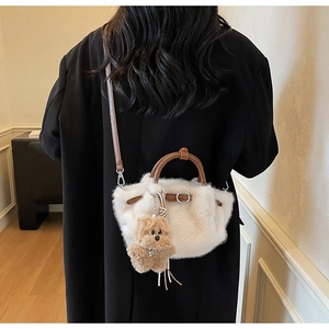Detail of white plush bucket bag with brown leather strap and small bear charm decoration