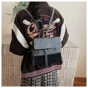 Close-up of retro grey and black crossbody bag with metallic brand logo and adjustable strap