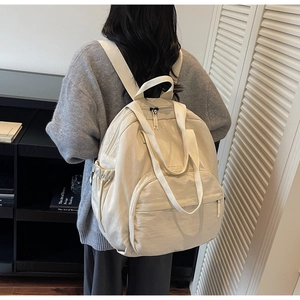 View of the beige large capacity nylon backpack on a model in a modern interior setting