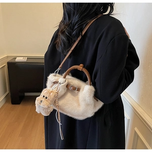 Detail of plush faux fur bucket bag with leather strap and cute puppy charm accessory