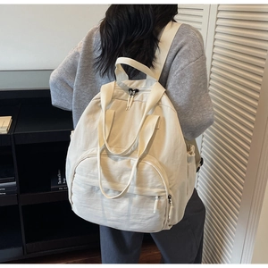 Rear view of woman wearing large off-white nylon backpack with adjustable straps