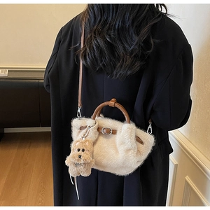 Detail view of cream plush bucket bag with brown leather handles and puppy charm