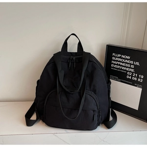 Detail of black nylon backpack with multiple zippers on white marble surface