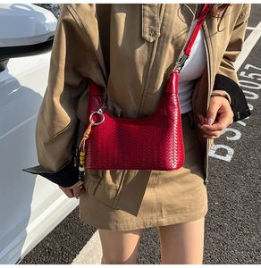 Detail view of red woven shoulder bag with bohemian beaded tassel charm and leather strap