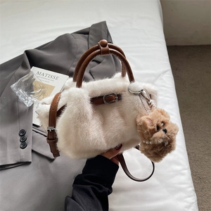 Close-up of white plush bucket bag with brown leather straps and cute puppy charm