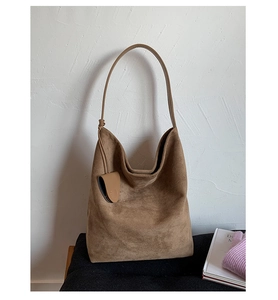 Detail showing high-quality brown suede texture and handcrafted knot on a large hobo bag