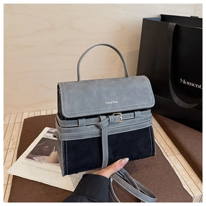 Detailed close-up of gray and black suede contrast crossbody bag with metal buckle