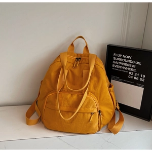 Detail of ginger yellow nylon backpack with multi-pocket design and water-resistant texture