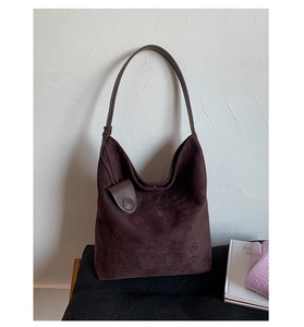 Detailed close-up of dark brown suede hobo bag featuring knotted shoulder strap and side pouch