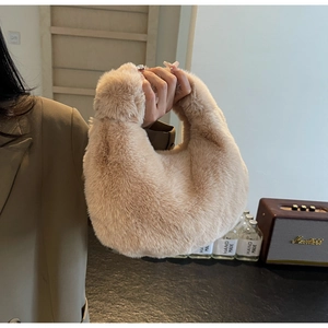 Détail du sac hobo en fausse fourrure pelucheuse crème tenu dans un cadre chaleureux