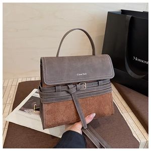 Close-up of retro color-block handbag showing brown suede texture and metal buckle detail