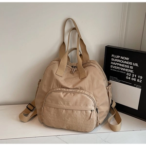 Detail of multi-functional khaki nylon backpack showing side pockets and thick straps