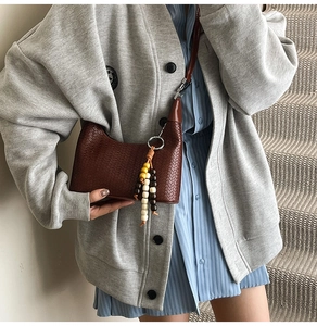 Detail of woven texture dark brown hobo shoulder bag with colorful beaded tassel charm