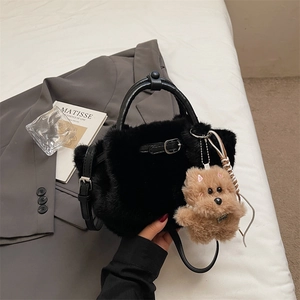 Close-up of black faux fur plush bucket bag with leather handle and cute puppy charm