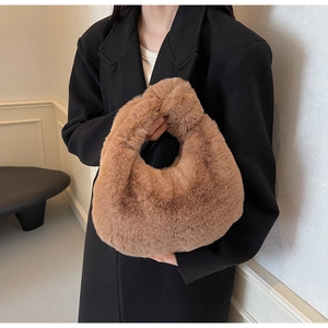 Détail d'un sac à main en fausse fourrure marron porté avec un manteau en laine noir