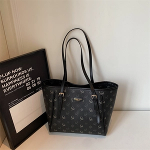 Détail de la plaque logo dorée sur un sac cabas noir avec motifs de cerfs imprimés
