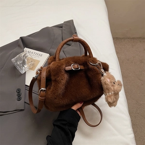 Detailed macro view of brown faux fur handbag texture with a cute plush bear keychain charm