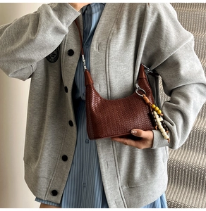 Detail of dark brown woven leather hobo bag with colorful wooden bead tassel accessory