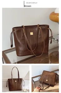Detailed close-up of mud-colored tote bag with gold buckle and decorative drawstrings