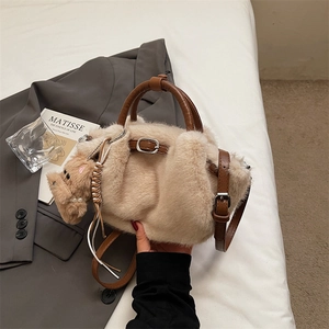 Detail of plush beige bucket bag with brown leather handle and cute puppy charm