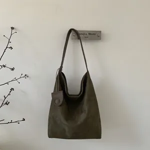 Close-up of olive green suede hobo bag with leather strap and mini pouch charm