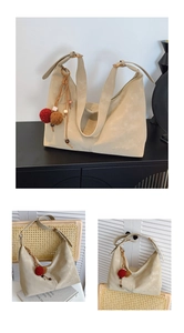 Detail der minimalistischen beigefarbenen Hobo-Tasche mit breitem Gurt und Deko-Anhänger