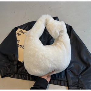 Gros plan du sac à main en fausse fourrure blanche posé sur une veste en cuir noir