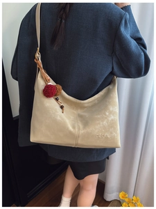 Detailaufnahme der beigen Hobo-Tasche mit strukturierter Oberfläche und Pelzanhänger