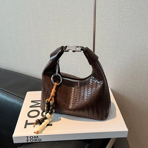 Detail of dark brown woven leather hobo bag with colorful wooden bead tassel and metal buckle