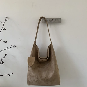 Detail of soft khaki suede hobo bag with round leather pendant and minimalist design