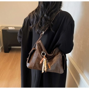 Detail of vintage brown leather dumpling bag with decorative beaded tassel and side snap pocket
