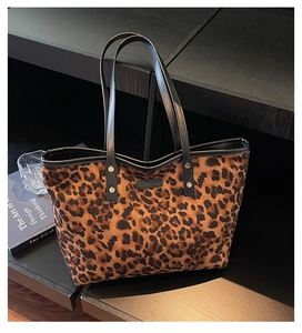 Detail of leopard print tote bag on a black bookshelf with artistic decor accents