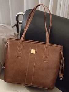 Brown faux leather tote bag with gold metal square buckle and adjustable shoulder strap