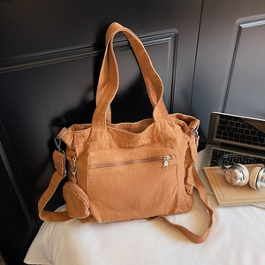 Détail d'un sac cabas en toile marron avec anneaux métalliques et bandoulière amovible