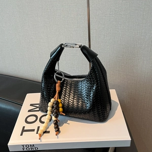 Detail of black woven leather handbag showing silver buckle and colorful beaded tassel charm