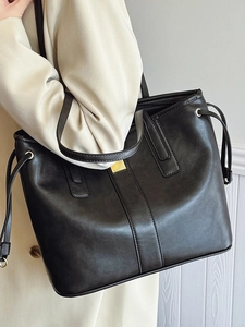 Minimalist large capacity black tote bag with gold metal hardware and shoulder strap