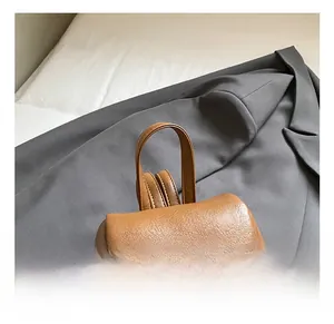 Detail view of brown lychee texture leather handle and golden brand logo on bag cover