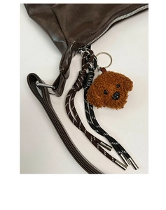 Détail du sac cabas en cuir marron avec breloque chien en peluche et cordons tressés