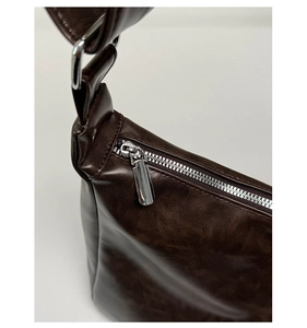 Détail de la fermeture éclair en métal argenté sur un sac en cuir huilé marron