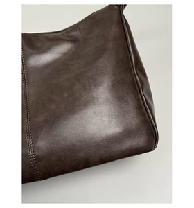 Gros plan des coutures fines et de la texture du cuir ciré vintage sur le sac fourre-tout