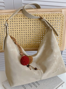 Große beige Hobo-Schultertasche aus mattem Material mit MERFIL-Logo auf einem Stuhl