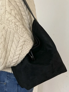 Minimalist black faux suede shoulder tote bag worn by a model in casual knitwear