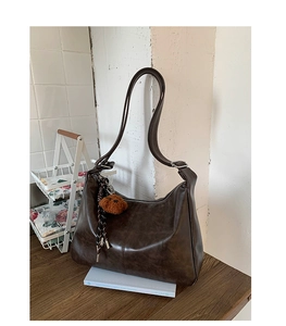 Détail d'un sac en cuir PU marron café avec coutures vintage et pendentif ours en peluche