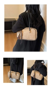 Detail view of khaki suede shoulder bag featuring wood bead accents and fringe pendant