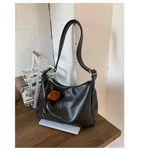 Détail d'un sac à bandoulière en cuir mat avec breloque ours et porte-clés tissé