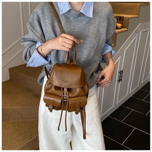 Detail view of a vintage brown mini backpack with front buckle pockets and slim straps