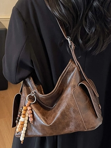 Deep brown leather hobo bag with vintage texture and beaded tassel charm in side view