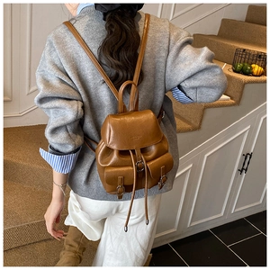 Detailed back view of a retro brown leather backpack worn by a model in casual setting