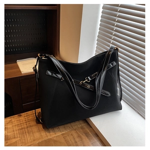Détail du sac cabas noir avec texture en toile mate et accents en cuir verni brillant